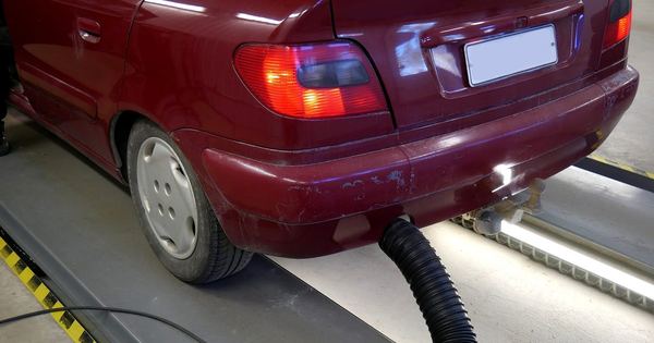 Autoturism pe linia de verificare, cu furtunul pentru măsurarea gazelor de eșapament la țeava de evacuare
