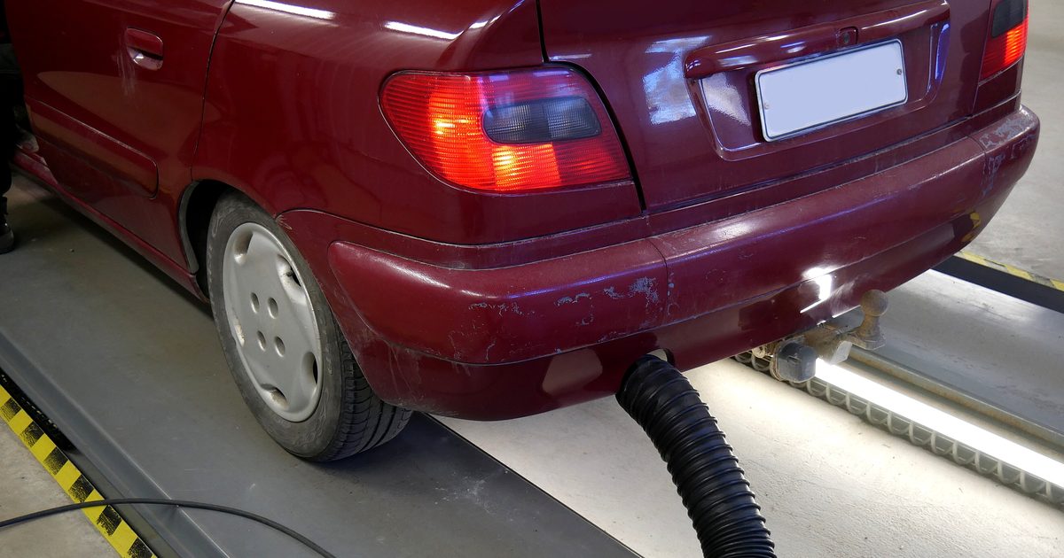 Autoturism pe linia de verificare, cu furtunul pentru măsurarea gazelor de eșapament la țeava de evacuare