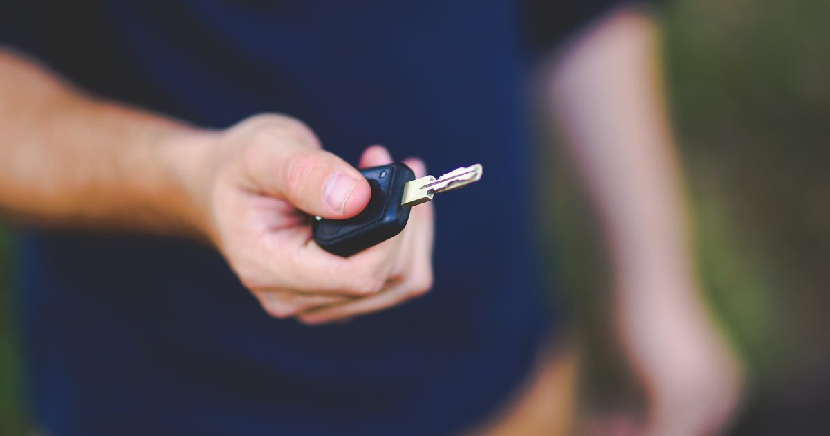 Mână care întinde o cheie de mașină, ca la predarea autoturismului către noul proprietar